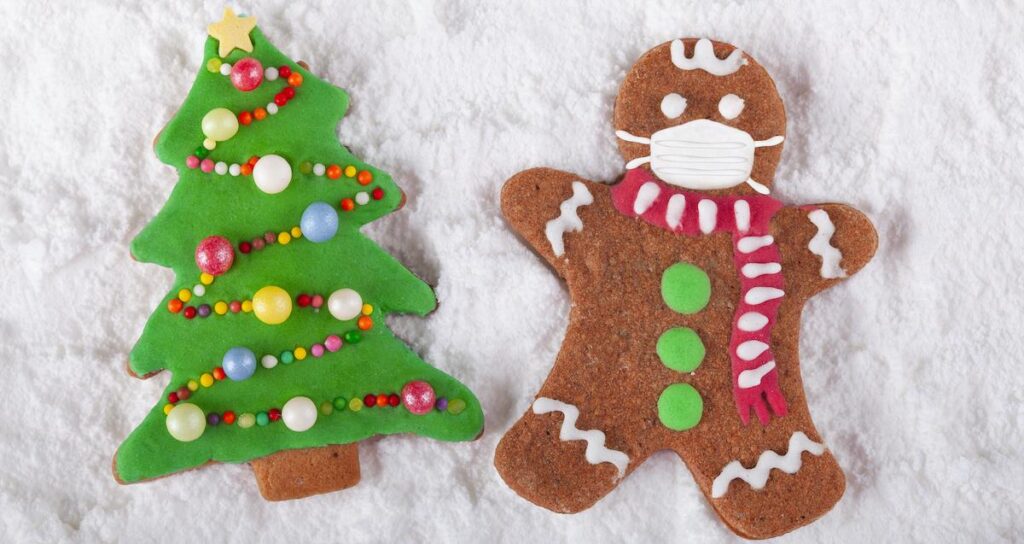 Image of two gingerbread cookies. One looks like a Christmas tree, and one has a gingerbread man in a Covid mask.